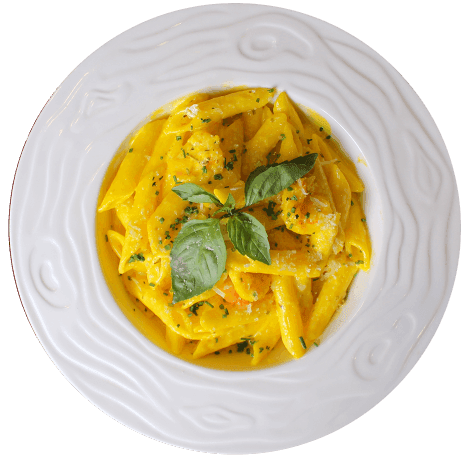 Prato branco com massa tipo penne envolta em molho cremoso de cor alaranjada e guarnecido com folhas de manjericão fresco, servido no Restaurante Bellissima Italia